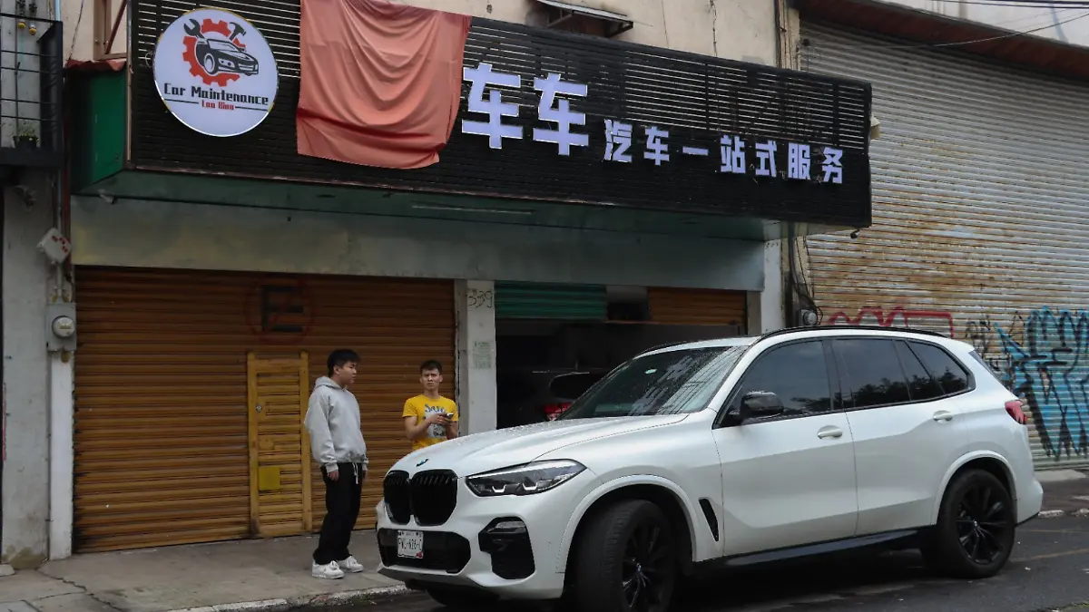 migrantes chinos frente a negocio de mantenimiento de autos